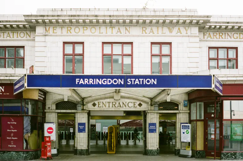A train station with a yellow and blue sign that says "Farringdon Station".