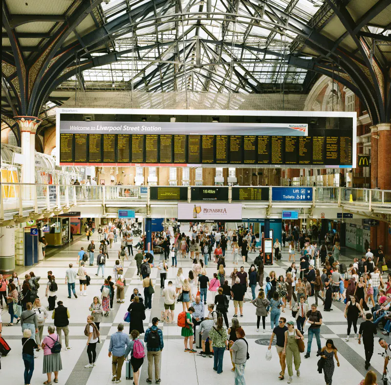 A large group of people are walking around in a train station.