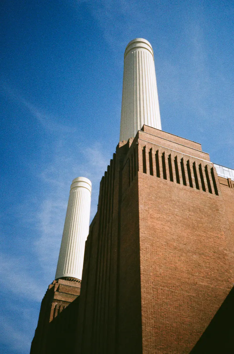 Two large towers with a white top and a large brick building in the background.