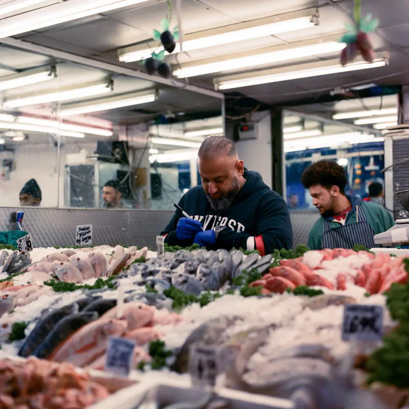 A man in a blue glove is writing on a piece of paper in front of a fish display.
