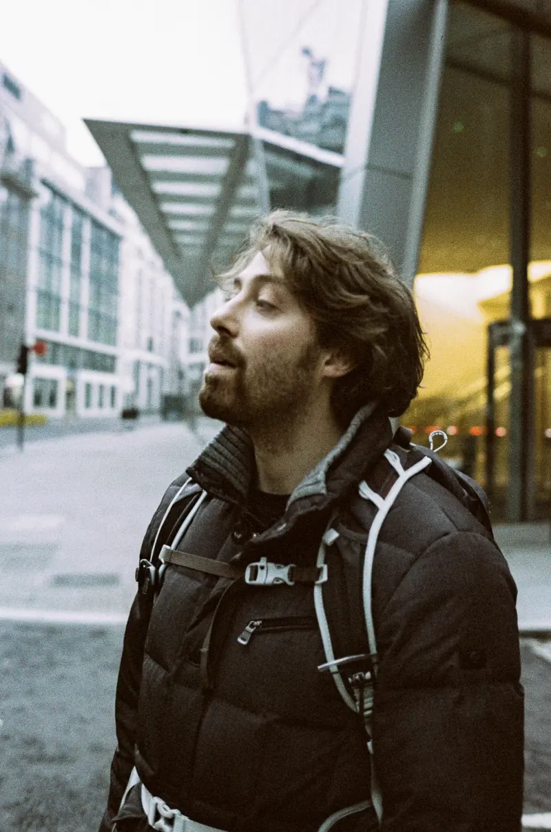 A man wearing a backpack and a gray jacket.