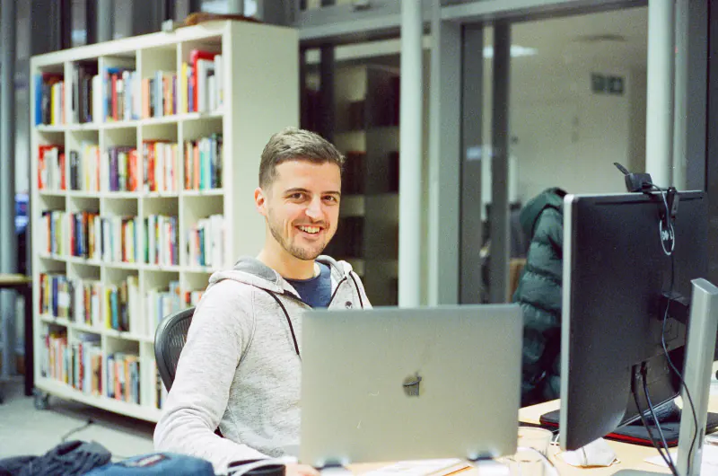 A man is sitting at a desk in front of a laptop.