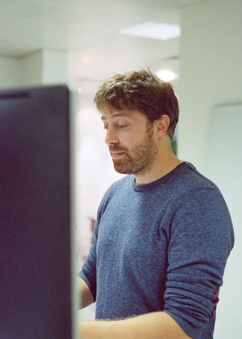 A man wearing a blue shirt is looking at a computer screen.