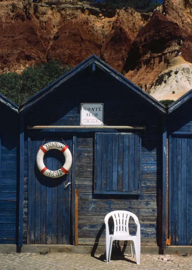 A blue shed with a white life preserver hanging on the door.