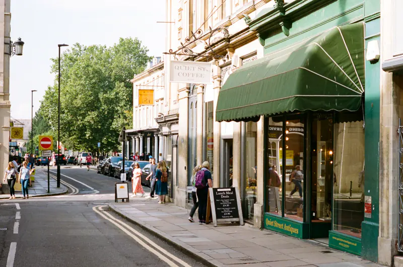People walking on a sidewalk in front of a store.