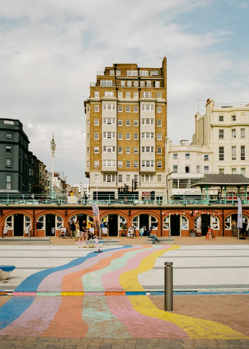A colorful sidewalk leads to a building with a clock tower.