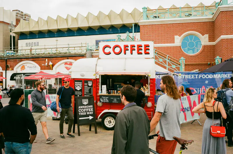 A group of people are standing in front of a red coffee truck.