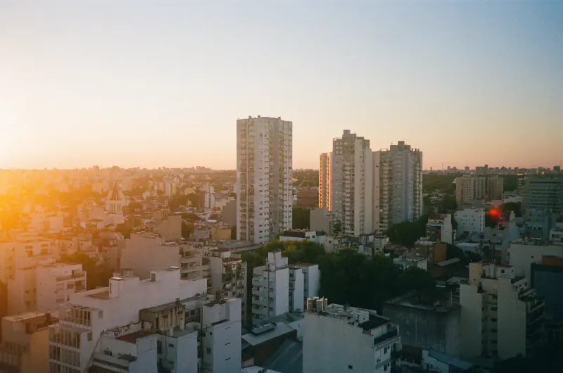 A cityscape with tall buildings and a sunset in the background.