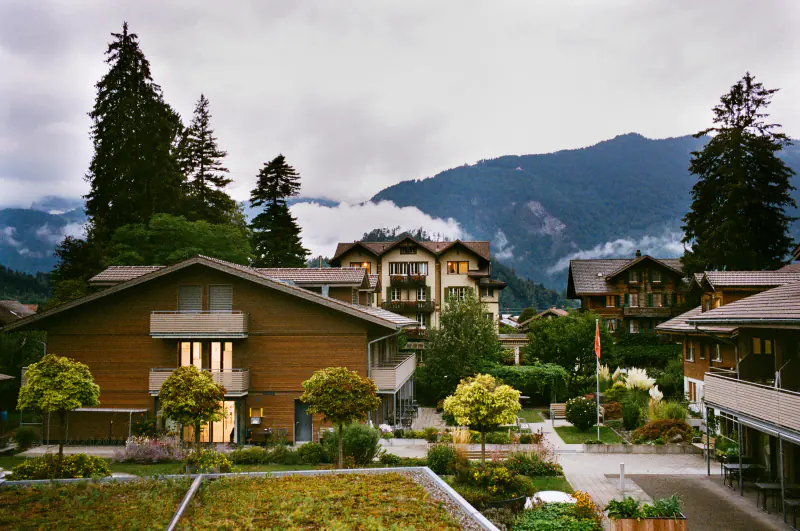 A large brown house with a green roof is situated in front of a mountain.