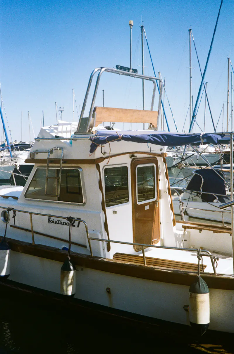 A boat with a blue tarp on it is docked at a marina.