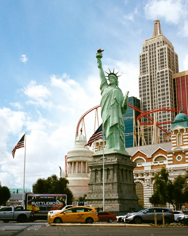 A statue of a woman holding a torch is located in front of a large building.