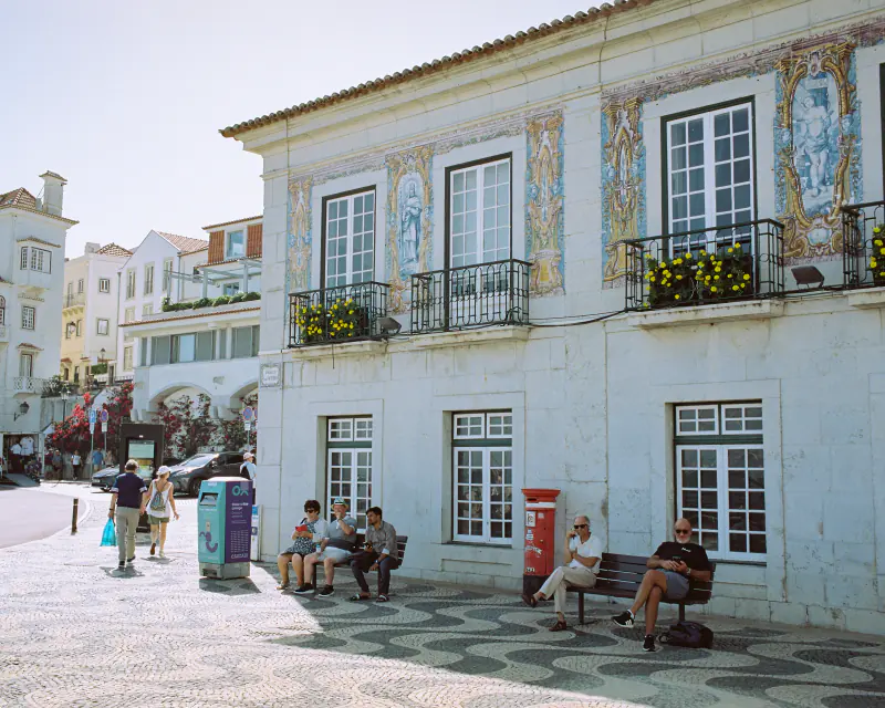 A group of people sitting on a bench in front of a building.