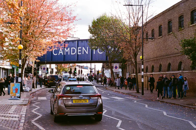 A car is driving under a bridge in a city.