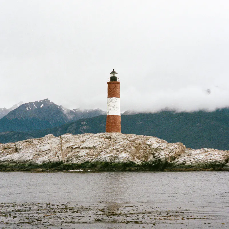A lighthouse is on a rock in the ocean.