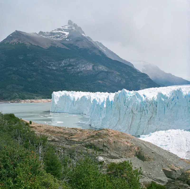 A large glacier is seen in front of a mountain.