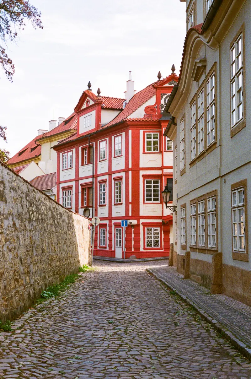 A narrow alleyway between two buildings, one red and one white.