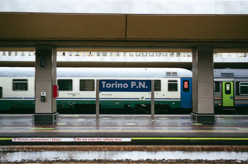 A train is parked at a station with a blue and white sign on the platform.